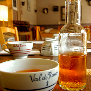 Pichet et verres de cidre sur table en bois au restaurant Le Petit Poucet, Saint-Léon