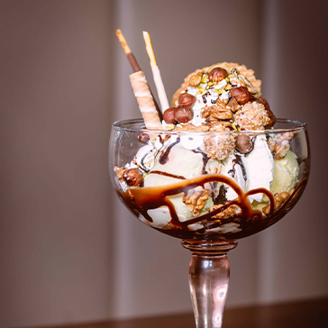 Coupe de glace avec fruits et garnitures sur fond sombre au Petit Poucet