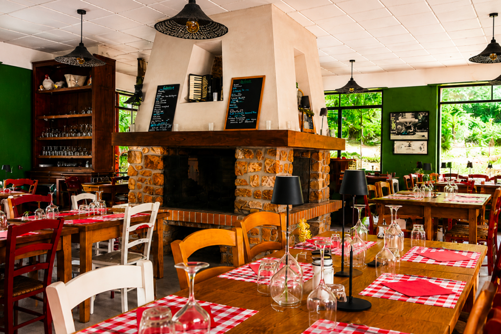 Intérieur rustique du Petit Poucet avec cheminée, tables et chaises en bois, Saint-Léon