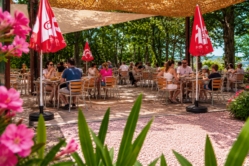 Terrasse du Petit Poucet avec parasols rouges et clients attablés, Saint-Léon Allier