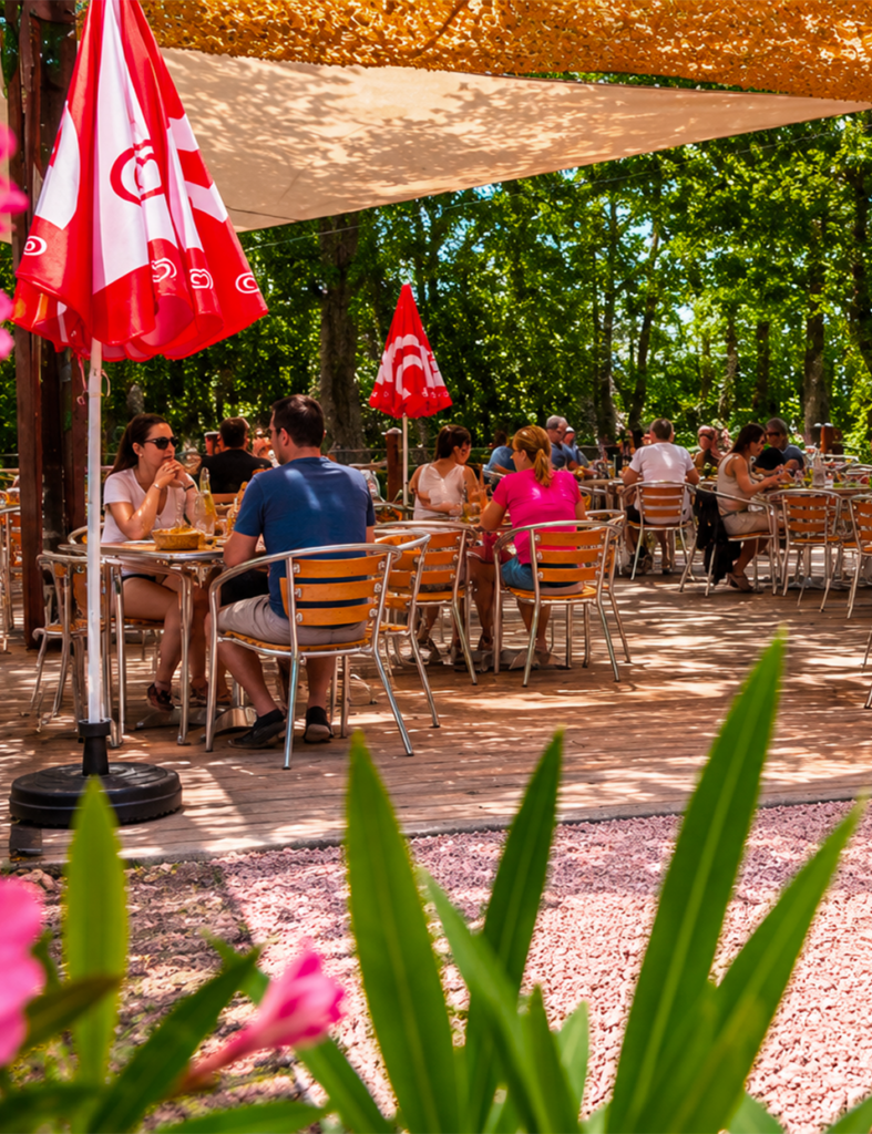 Terrasse animée du Petit Poucet avec clients et parasols rouges, Saint-Léon Allier